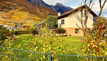 2 story house with brown roof, beige walls, green lawn, trees, plants, fence, view of mountains and vineyards