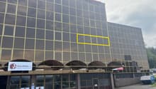 Large office building, glass windows, multiple stories, awnings over entrance, yellow highlighted window, DaKaPaint signage