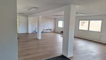 empty room, hardwood floor, white walls, 2 white pillars, 3 windows, radiator, ceiling lights
