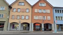Apartment building with three floors, multiple windows, entrance, restaurant area