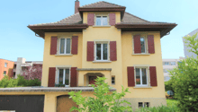 3-story house, yellow exterior, red shutters, wooden front door, visible garage, surrounded by greenery