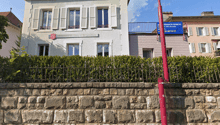 White house, red roof, white shutters, stone wall, greenery, parking pole