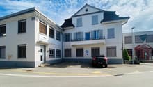 white building, three stories, parking lot, car parked in front