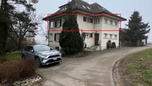 3-story house, beige color, many windows, chimney, paved driveway, a car parked in front