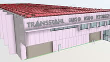 Large industrial or commercial building with a red tiled roof, the name 'Transstahl' prominently displayed on the facade, and a parking area visible in front of the building.