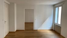 empty room, wooden floor, white walls, door, window, radiator