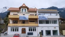 2 story building, brown roof, yellow balconies, white walls, parking lot in front