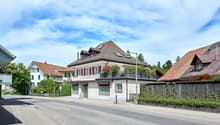 Swiss style houses, brown roofs, white walls, red shutters, balconies, green trees