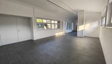 Empty room with white walls, gray tiled floor, large windows, and two white doors