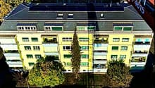 5 story yellow building, multiple balconies, many windows, solar panels