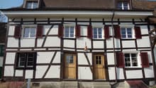 Two story house, white walls, brown trim, red shutters, two doors