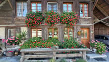 Traditional wooden house with flower boxes, wooden door, wooden bench, car parked in front