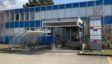 2-story blue and gray commercial building with a covered entrance, bicycle parking, and a directory sign indicating various businesses located inside.