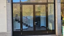 Modern building with glass doors and windows, concrete structure, staircase visible through the glass
