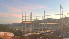 construction site with steel scaffolding, crane in the background, view of the mountains and horizon