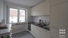 modern white kitchen with gray floor, large window with view, under cabinet sink and dishwasher, built-in oven and dishwasher
