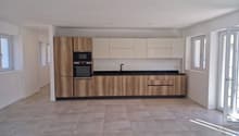 modern kitchen with wooden cabinets, tiled flooring, microwave, oven, sink, and a glass door