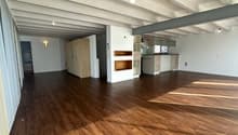 Open floor plan, wooden floors, white walls, kitchen with appliances, wooden cabinets, storage closet, hallway, bathroom