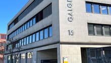 modern building with grey and black wall, multiple windows, text on wall 'GALGENFELD', grey garage entrance