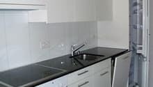 modern kitchen with white cabinets, black countertops, stainless steel sink, gas stove, oven, refrigerator, dishwasher, and a faucet