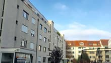 4 story building, balcony, garden with plants and grass, orange house in the background