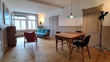 wooden floor, wooden table, blue sofa, red chair, wooden cabinet, lamp, tripod