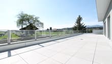 large balcony with glass railings, tiled floor, view of the surrounding landscape