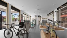 interior of a bicycle store with bikes on display, clothing racks, and large windows