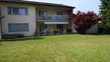 2-story house, beige exterior, terrace on the second floor, lawn, trees, plants, awning over the terrace