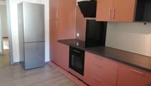 modern kitchen, with oven, refrigerator, brown wooden cabinets, white walls, wooden floor