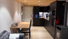 Living room with wooden floor, wooden ceiling, couch, coffee table, dining table, black fireplace
