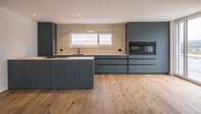 modern kitchen with island, wooden floor, gray cabinets, white countertops, built-in oven, sink, and faucet