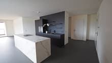 modern kitchen with marble countertop, black cabinets, stainless steel appliances, white walls, gray flooring