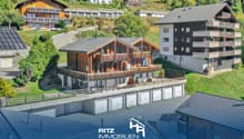 Two story wooden chalet, green roof, solar panels, balconies, several garages, view of the hills, large garden