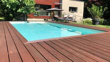 Swimming pool with wooden deck, lounge chairs, umbrellas, and plants