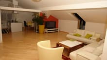 white leather couches, wooden coffee table, TV, potted plant, wooden floor, dining table and chairs, kitchen area