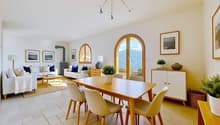 Dining room with a wooden table, white chairs, a white couch, a white cabinet, a wooden floor, and a chandelier