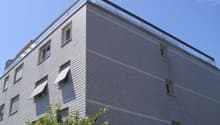 4 story building, brick facade, glass windows, glass balcony on top floor