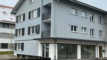 three-story apartment building with balconies, modern architecture, gray exterior, glass windows, front entrance