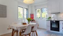 Dining room with a table, chairs, and a kitchen area with an oven and cabinets