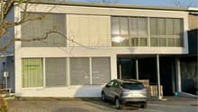 modern white building with many windows, a car parked in front, grey brick paving in front