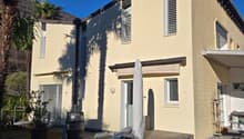 2 story house, yellow exterior, brown roof, balcony, patio, palm trees, barrel, potted plant