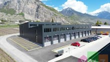 Large commercial building with multiple garage doors, parking lot, surrounded by mountains and vineyards