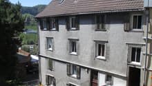 3 story house, brick exterior, 4 windows on each floor, brown roof, chimney, fenced pathway