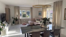 Dining room with a large table, chairs, a couch, a television, and a cabinet with a TV on top