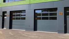 2-story commercial building with green and gray exterior, large windows, and garage doors