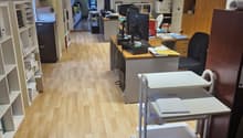 Modern office with desks, computers, bookshelves, and storage units, parquet flooring, office equipment