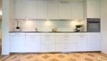 modern, white cabinets, black countertop, stainless steel sink, oven, flowers on countertop, wooden floor