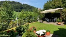 garden with seating area, dining table, canopy, greenery, lawn, and distant hills