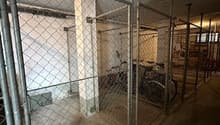 Metallic cage, parked bicycles, concrete floor
